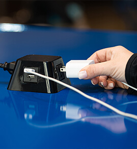 a woman plugging in her phone to charge while she waits for her laundry